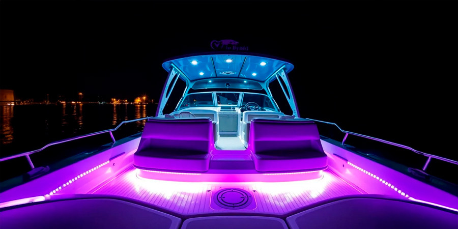 boat-led-lighting-purple-blue-night A luxury boat illuminated with purple and blue LED strip lights, highlighting the seating area and interior at night on the water.