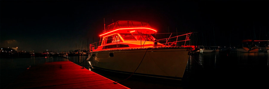 led-boat-lighting-night-dock-ambiance A boat illuminated with vibrant red LED strip lights, creating a striking and stylish look while docked at night.