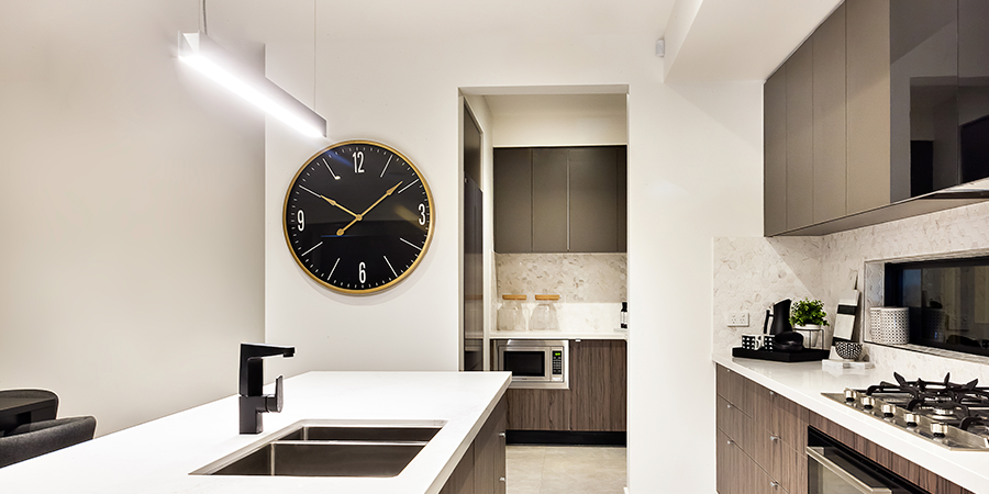 Kitchen interior with white countertops, black faucet, and wall clock